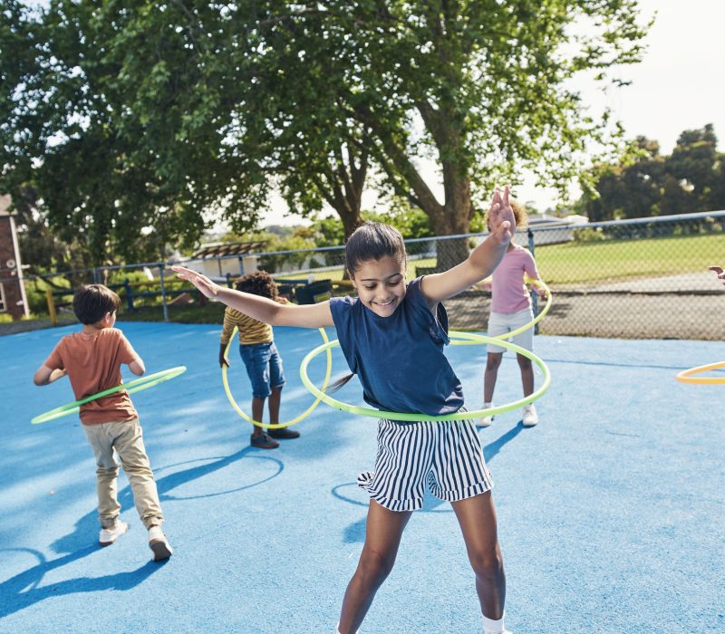 Children, hula hoop and friends playing outdoor together during break or recess on a school playground. Kids, games or fun with girl and boy students bonding while having fun outside during summer Children, hula hoop and friends playing outdoor together during break or recess on a school playground. Kids, games or fun with girl and boy students bonding while having fun outside during summer