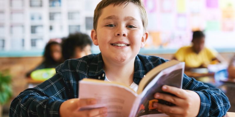 Shot of a young boy sitting in his classroom at school and reading a book My love of reading developed in school