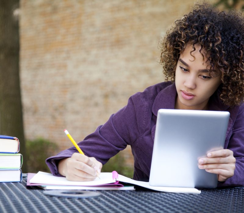 Woman using a digital tablet to study Ethnic woman with curly hair using an e-reader or digital tablet to study.