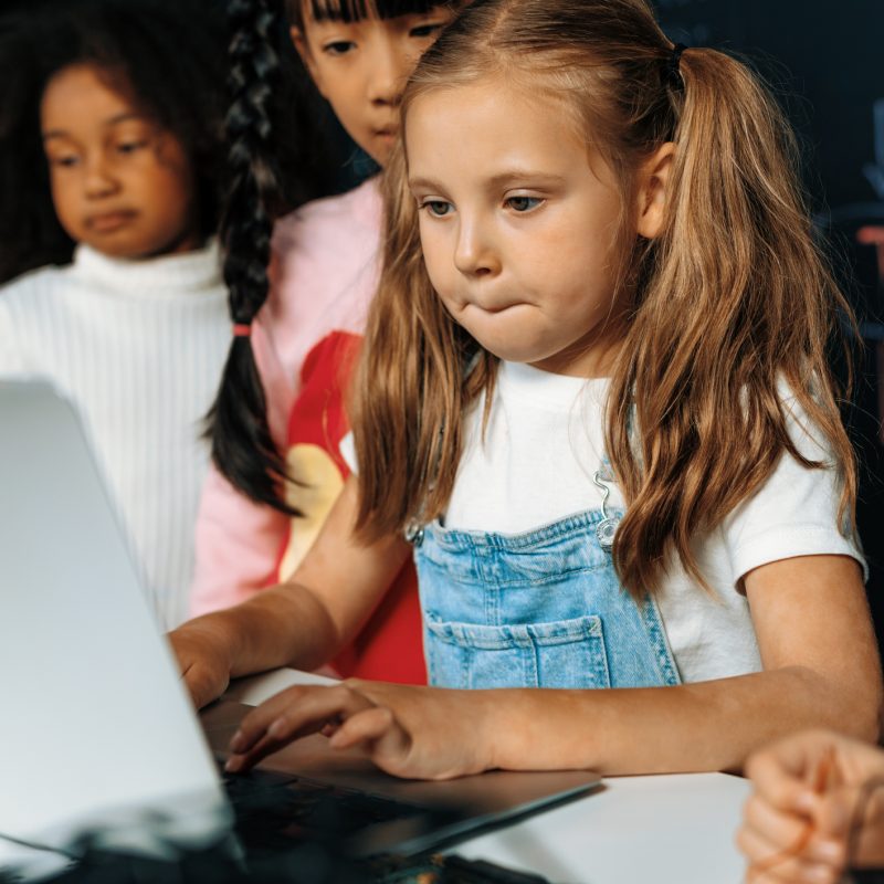 Smart girl in white bib learning robotics technology using laptop. Erudition. Smart girl in white bib learning about coding robotics technology using laptop in the STEM class. Schoolboy in blue shirt try to educate motherboard while smart schoolgirls reading code. Erudition.
